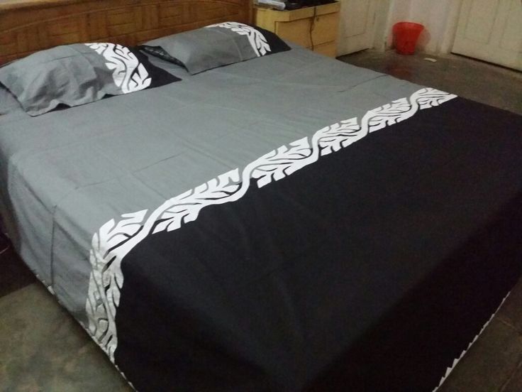 a bed with black and white bedspread on top of it in a room