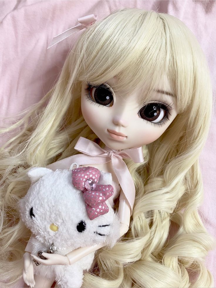 a doll with long blonde hair holding a hello kitty stuffed animal