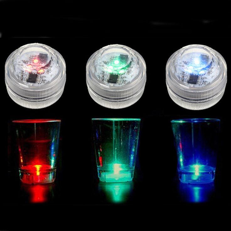 four different colored lights in front of a remote control and three shot glasses with one light on each side