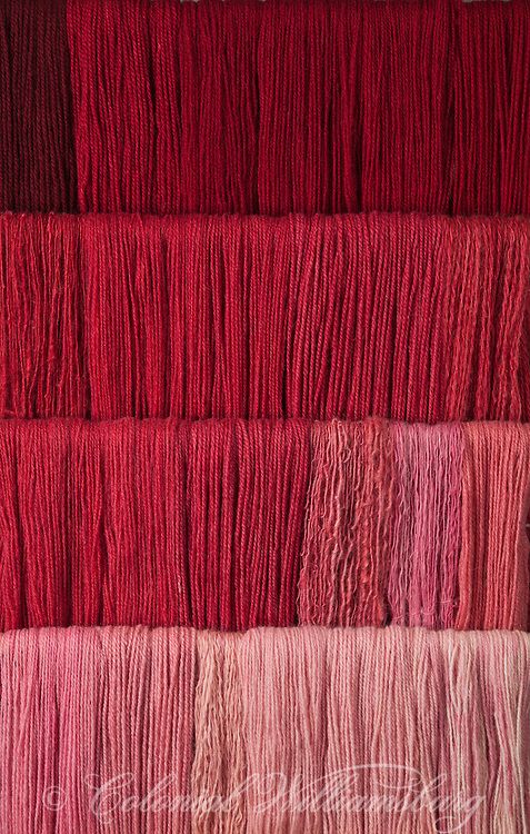 red and pink yarns are arranged in rows on a table with the words,