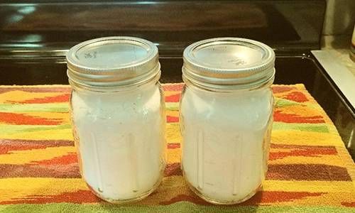 two mason jars sitting on top of a colorful towel in front of an oven door