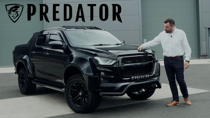 a man standing next to a black truck in front of a building with the words predator on it