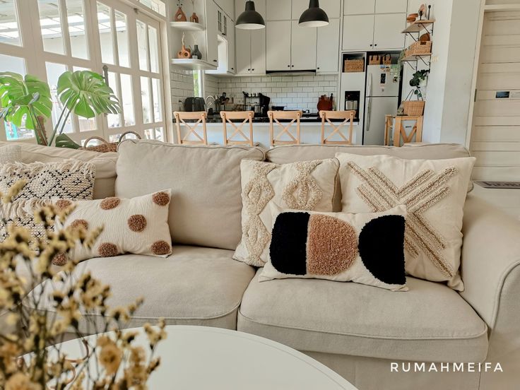 a living room filled with lots of furniture and pillows on top of a white couch