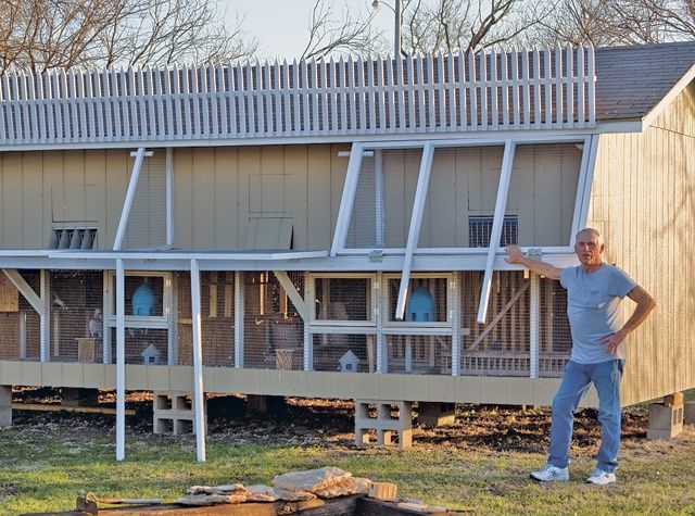 a man standing in front of a house with windows on the roof and side walls