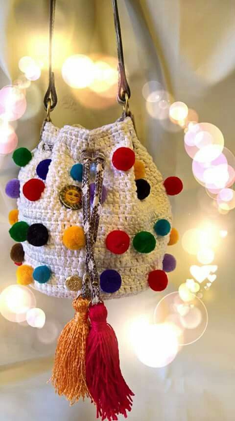 a white purse with multicolored pom poms hanging from it