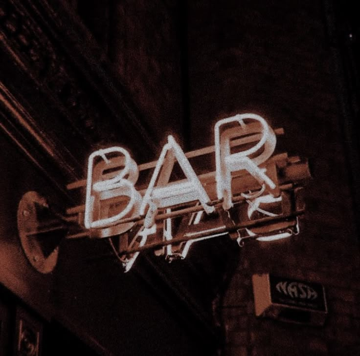 a neon bar sign is lit up on the side of a building