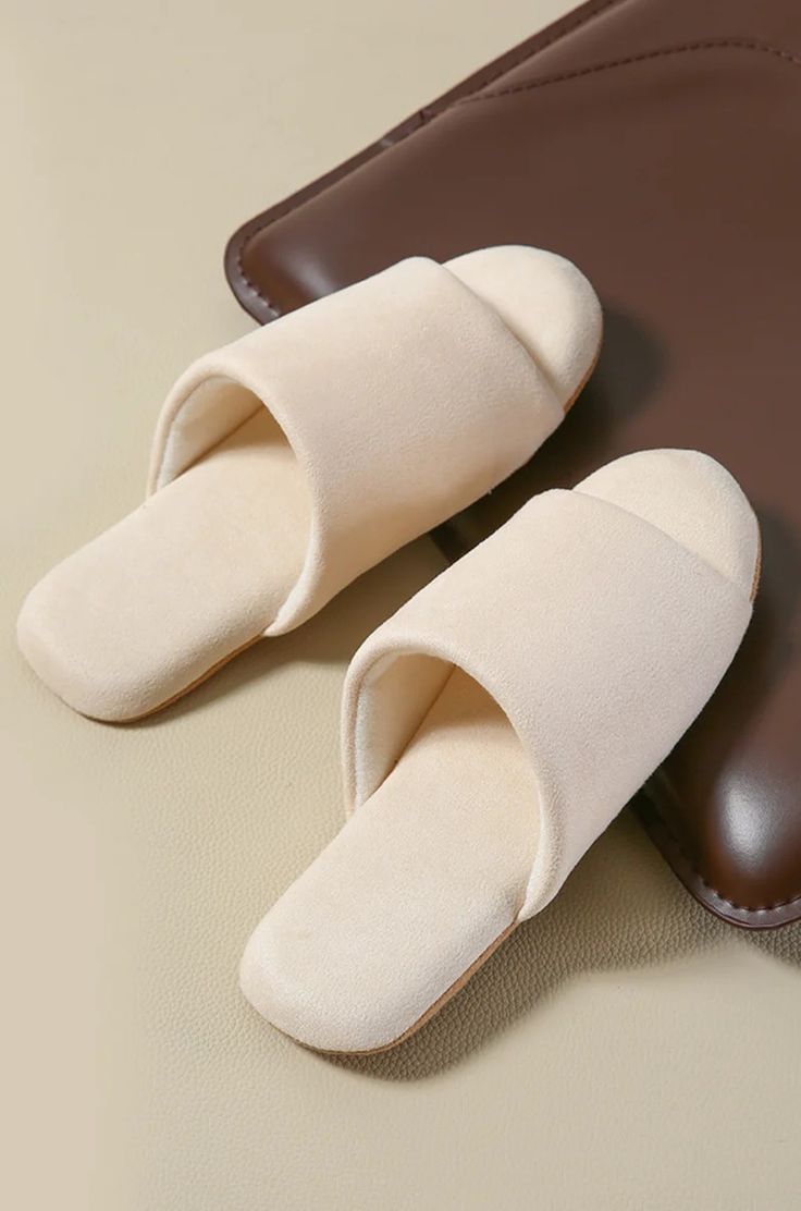 a pair of white slippers sitting on top of a brown bag