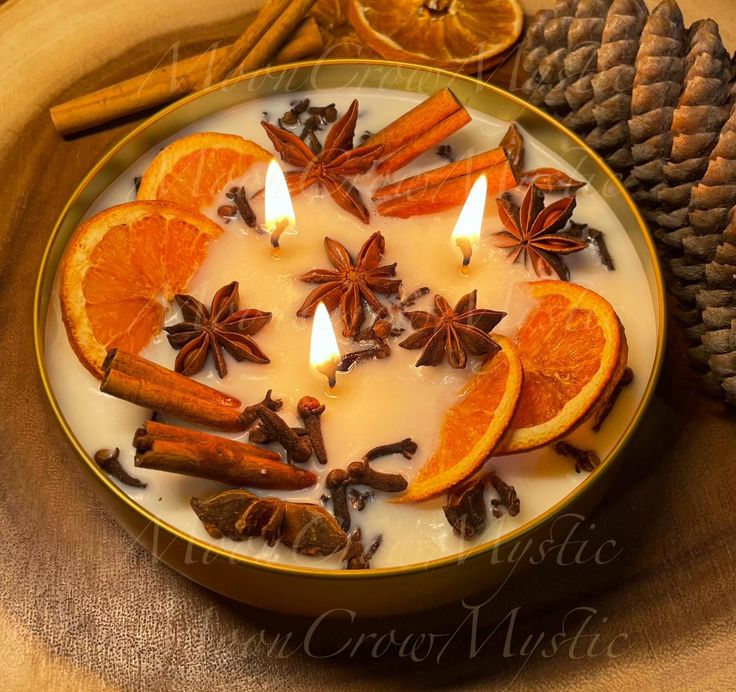 an orange and cinnamon candle surrounded by spices