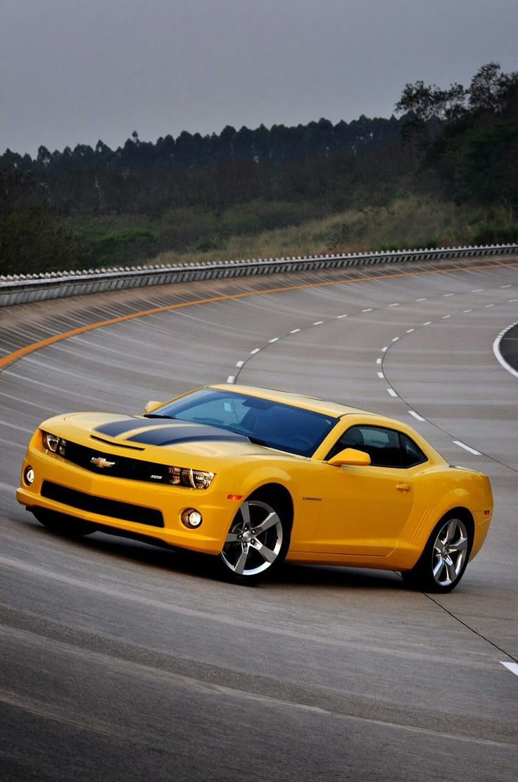 a yellow chevrolet camaro is driving down the road