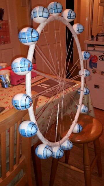 a ferris wheel made out of paper machs on a kitchen table with other items in the background