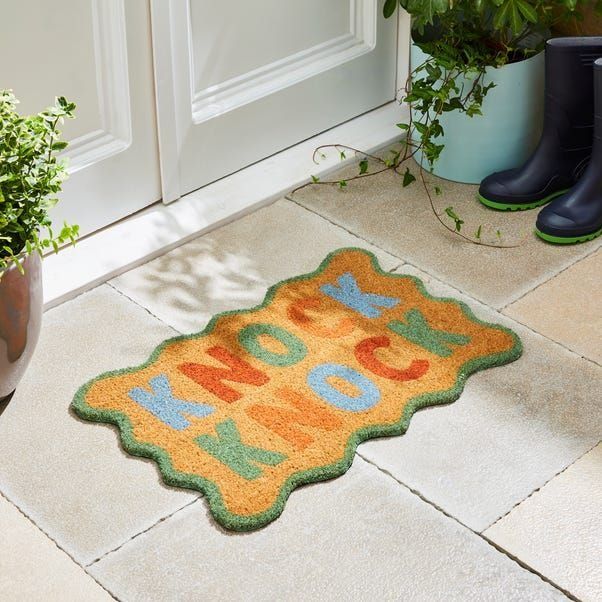 a pair of rubber boots sitting next to a potted plant in front of a door