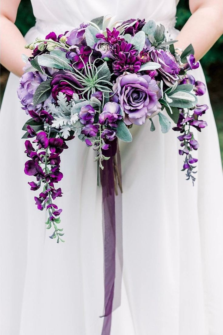 a bride holding a purple bouquet in her hands