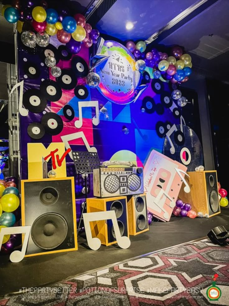 a stage set up with speakers, balloons and music notes on the wall behind it