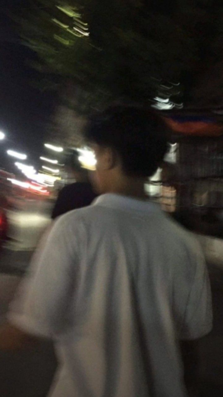 a blurry photo of a man riding a skateboard down a street at night