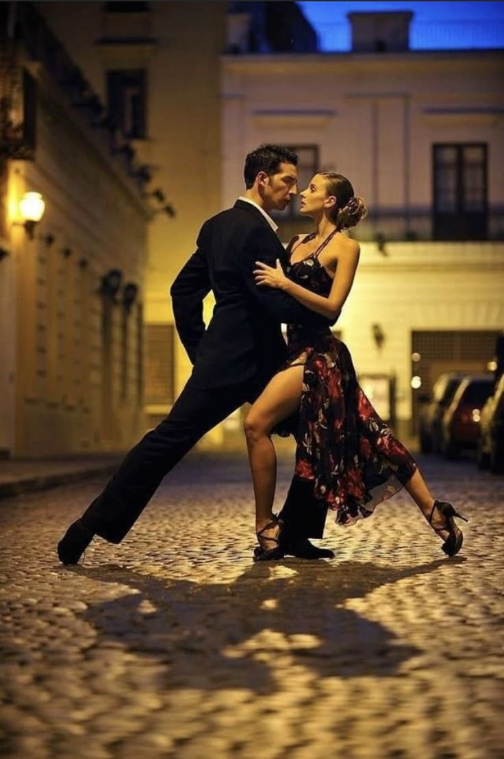 a man and woman are dancing in the street at night with their arms around each other