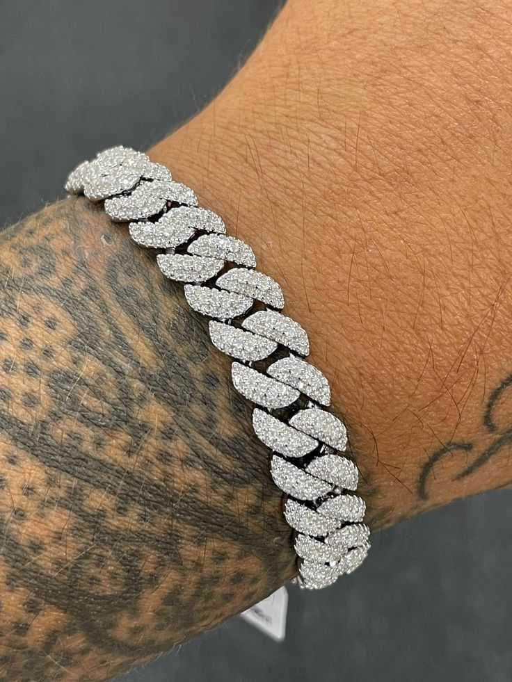 Unveil unparalleled brilliance with our 12mm Big Rock Moissanite Cuban Link Bracelet. Featuring a stunning 12mm moissanite stone, this bracelet is designed to make a bold statement with its exceptional sparkle and commanding size. The luxurious moissanite is set within a robust Cuban link chain, blending modern elegance with classic sophistication. Perfect for those who seek both standout style and timeless appeal, this bracelet adds a touch of opulence to any ensemble. Elevate your accessory co Iced Out Diamond Bracelet, Dazzling Silver Moissanite Bracelets, White Diamond Cuban Link Bracelets, Iced Out Diamond Cuban Link Bracelet, Luxury White Bling Bracelets, Luxury White Bracelets With Bling, White Moissanite Round Cut Bracelet, White Diamond Iced Out Bracelet, Diamond White Iced Out Cubic Zirconia Bracelets