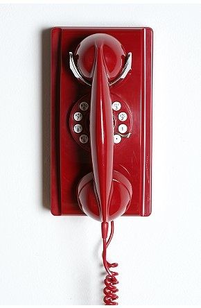 an old fashioned red telephone is hanging on the wall with two handset holes in it