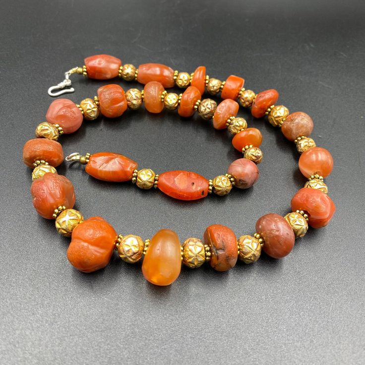 The Rare Unique PEMA RAKA Carnelian Amulet Prayer Beads Necklace From Himalayan Tibet The Age Of This Beads Are More than 1000 years Old As You Can See From Its Conditions Very Oily Smooth Skin Of This Pema Beads Some Gold Plated Wax and Gold Color Brass Beads Are Used As Spacers Rare Items For Collections Traditional Carnelian Round Bead Necklace, Traditional Carnelian Bead Necklace, Traditional Carnelian Oval Bead Necklaces, Traditional Carnelian Oval Beads Necklace, Traditional Carnelian Necklace With Polished Beads, Traditional Carnelian Gemstone Jewelry, Traditional Amber Gemstone Beads And Cabochons, Traditional Orange Beads For Jewelry Making, Traditional Orange Beaded Gems And Cabochons