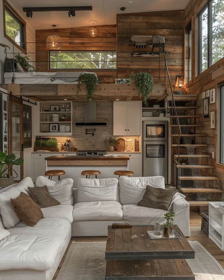 a living room filled with furniture next to a kitchen and staircase leading up to the top floor