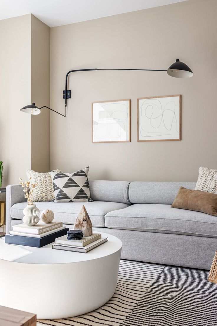 Neutral living room with beige walls, grey sofa, white concrete coffee table, abstract wood framed art and black double sconce above sofa. Living Room Design Beige, Greige Living Room, Gray Sofa Living, Grey Walls Living Room, Grey Sofa Living Room, Living Room Wall Color, Room Wall Colors, Living Room Renovation, Grey Sofa