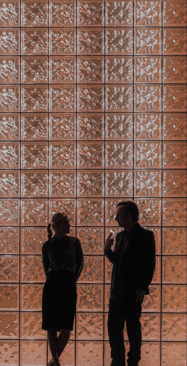 two people standing in front of a glass wall