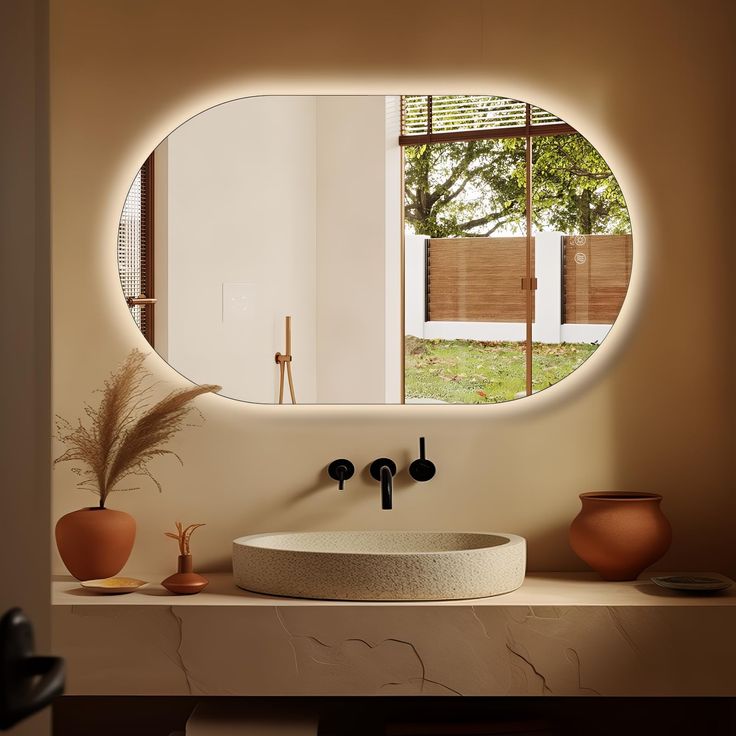 a bathroom sink with a circular mirror above it and vases on the counter top