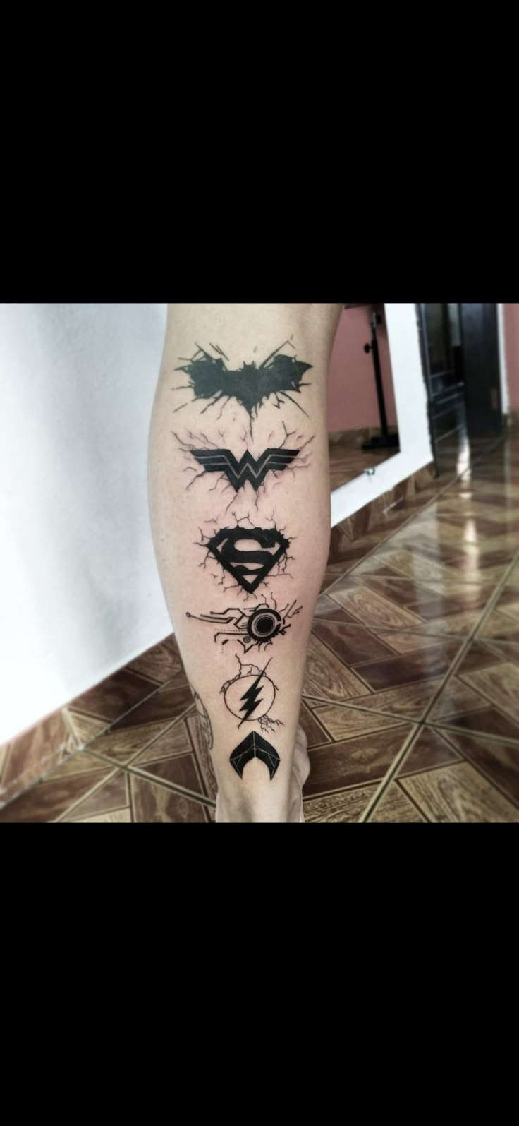 a person's leg with tattoos on it, including the batman symbol and other symbols