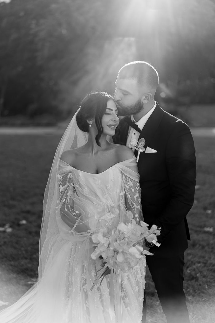 a bride and groom pose for a photo in front of the sun at their wedding