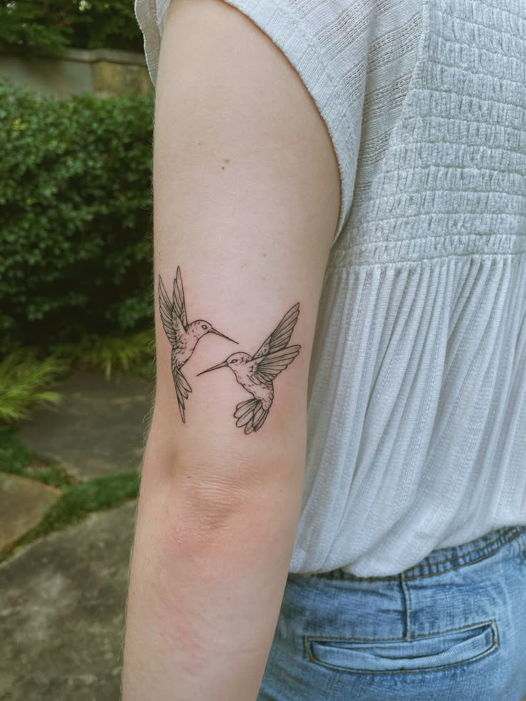 a woman's arm with a small hummingbird tattoo on the left inner arm