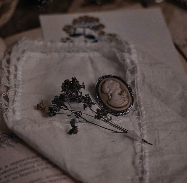 an antique button and some flowers on a piece of paper with lace around it sitting on a table