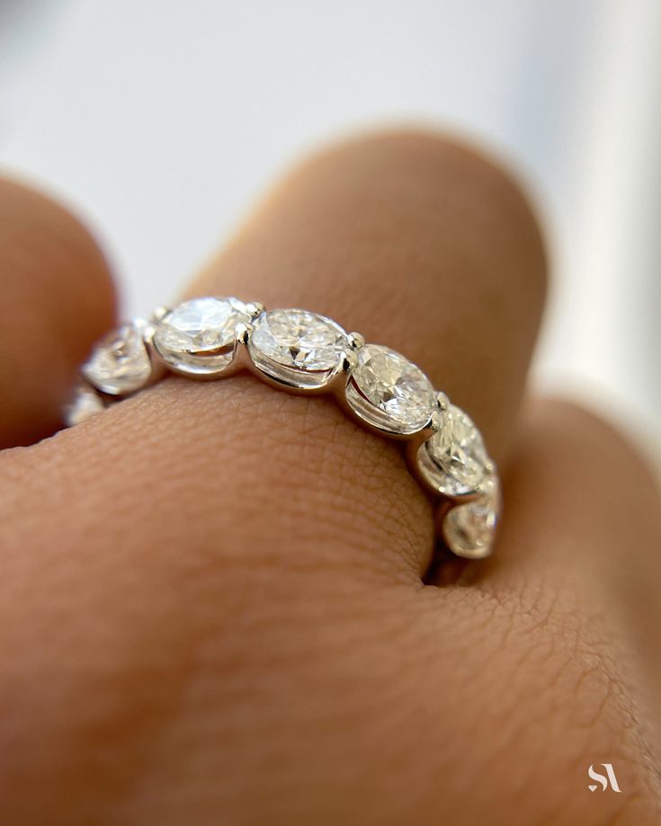 a woman's hand with a diamond ring on top of her finger, close up