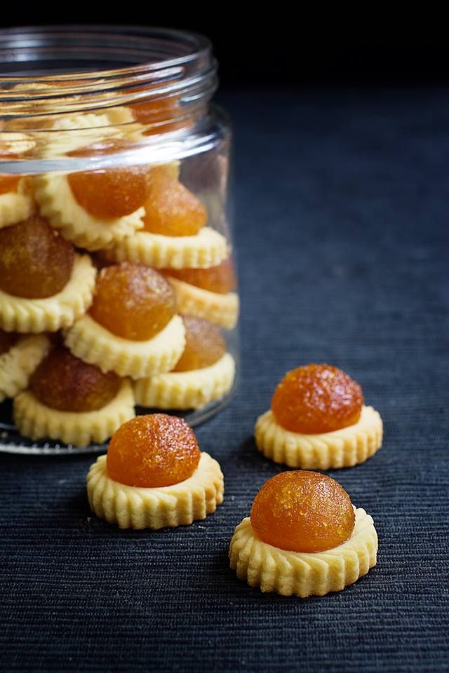 small pastries sitting in front of a glass jar filled with orange marmalade