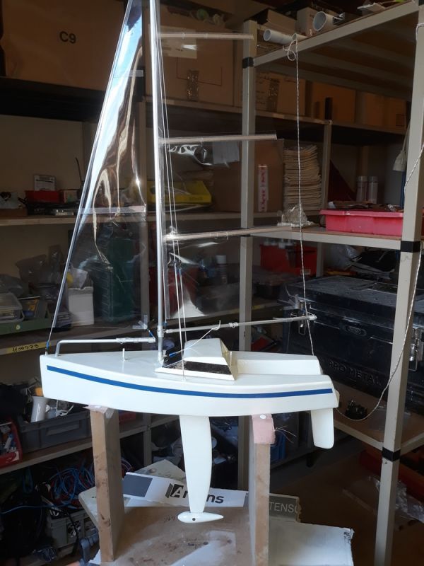 a model sailboat sitting on top of a wooden table in a room filled with shelves