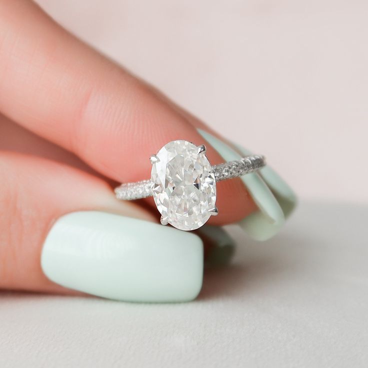 a woman's hand holding an oval diamond ring