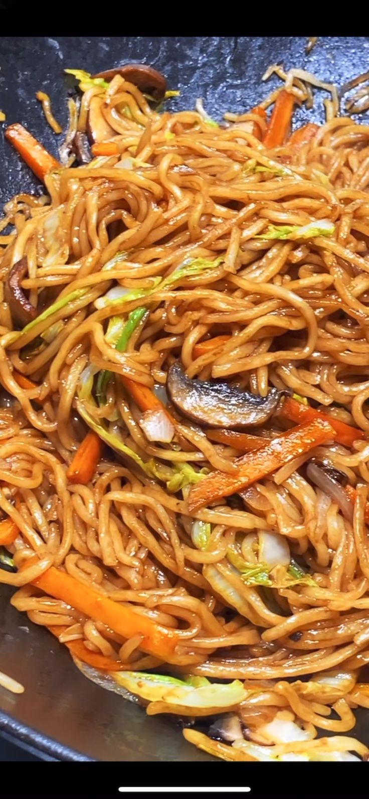 noodles and vegetables being cooked in a wok