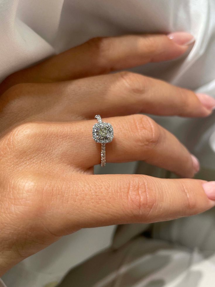 a woman's hand with a diamond ring on top of her finger and the other hand holding an engagement ring