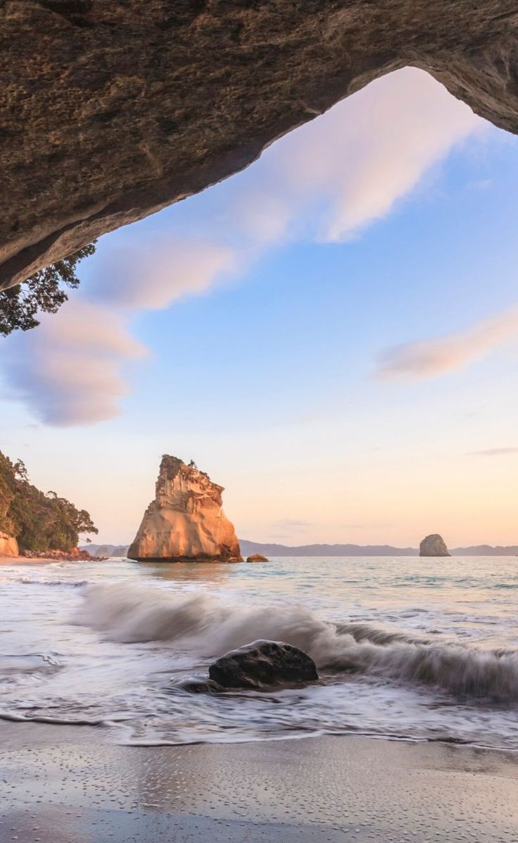 an ocean cave with waves coming in from the water and some rocks on the shore