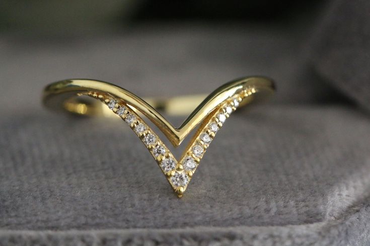 a gold ring with diamonds on it sitting on top of a gray cushioned surface