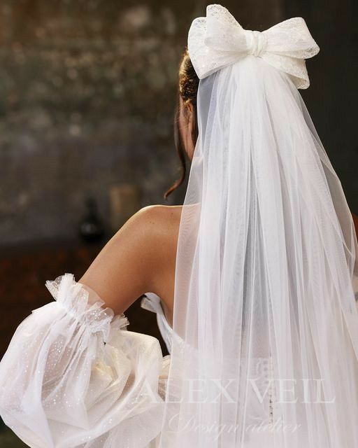 the back of a bride's wedding dress with a bow on her head and veil