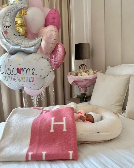 a baby is laying in a bed with balloons