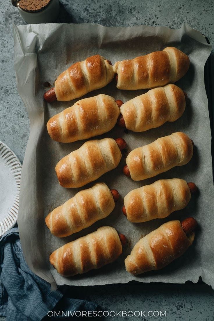 hotdogs wrapped in bread sitting on top of a paper plate