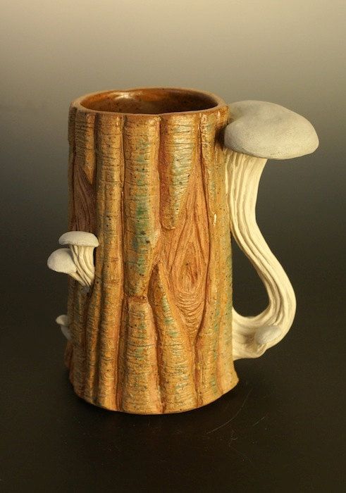 a wooden mug with two mushrooms on the inside and one in the outside, sitting on a black surface