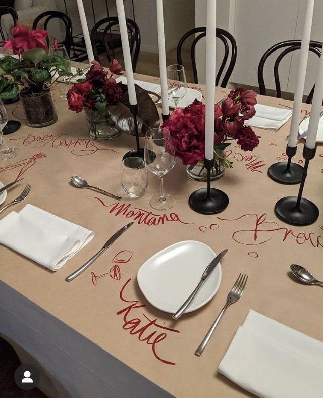 the table is set with white plates and silverware, red flowers, and candles