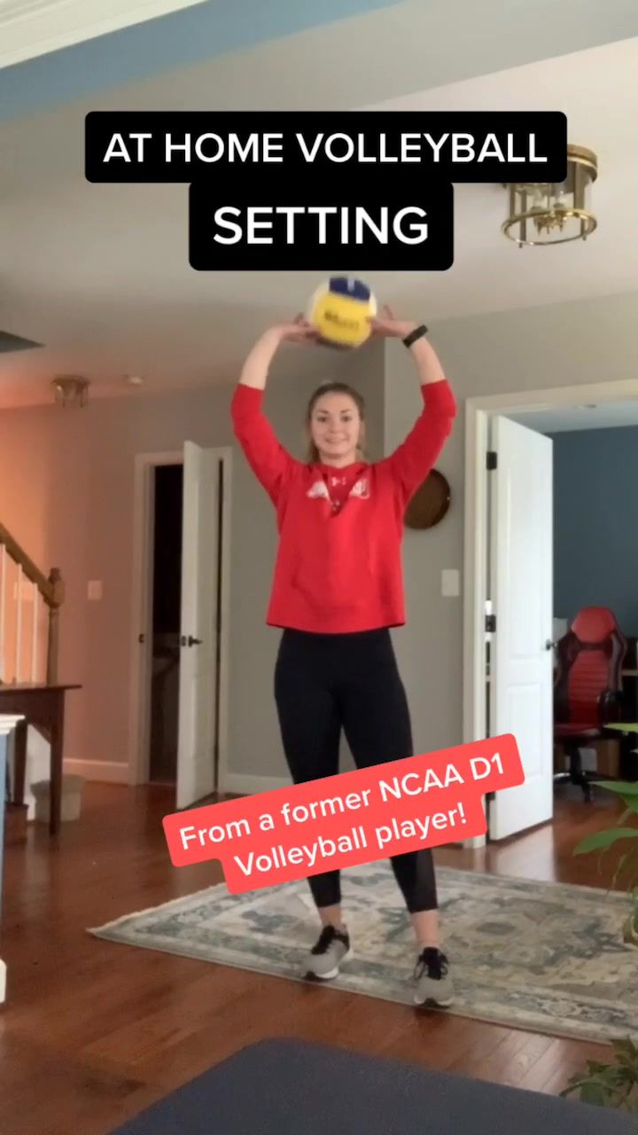 a woman in red shirt standing on top of a rug holding a yellow and black ball