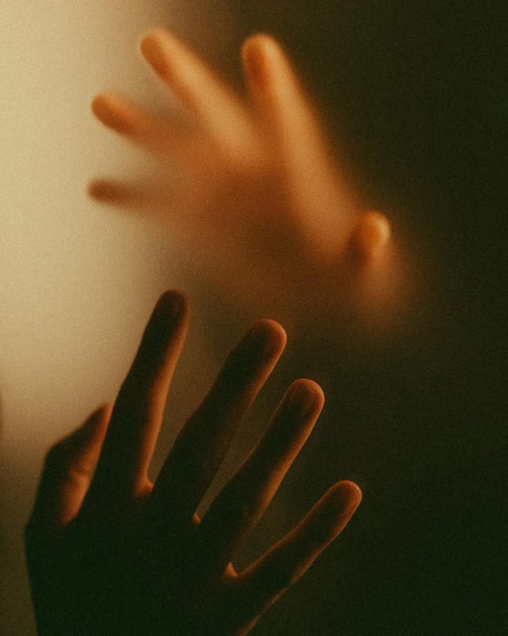 a blurry image of someones hand reaching out to touch the wall with their fingers