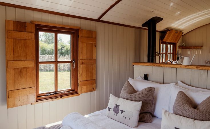 a bed in a room with two pillows on top of it and an open window