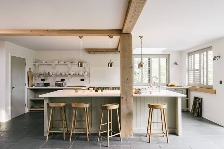 an open kitchen with bar stools next to the sink and stove top oven in it