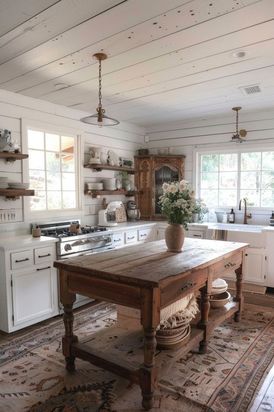 an old fashioned kitchen with white cabinets and wood table in the middle of the room