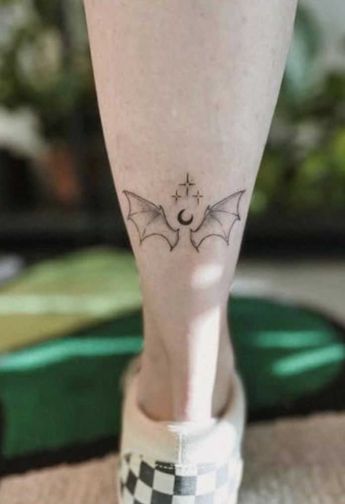 a woman's foot with a small bat tattoo on her left leg and the bottom part of her legs