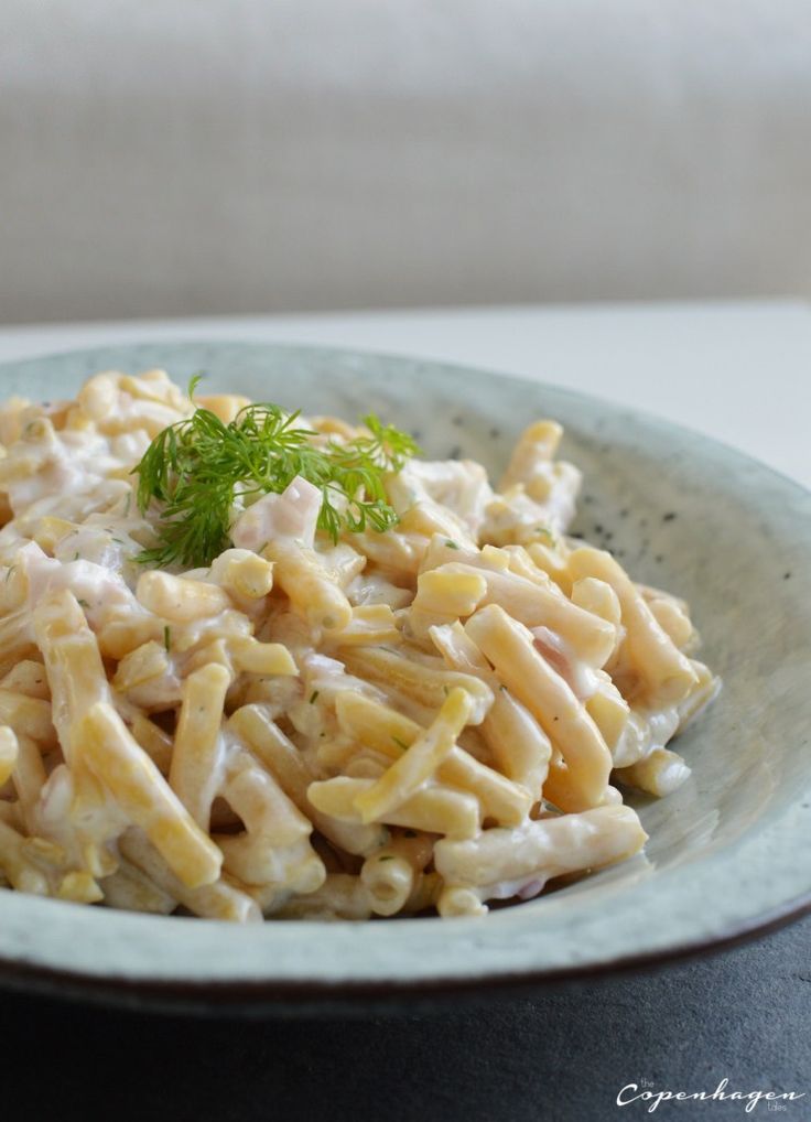 a pasta dish with chicken and parsley in a white bowl on a black table